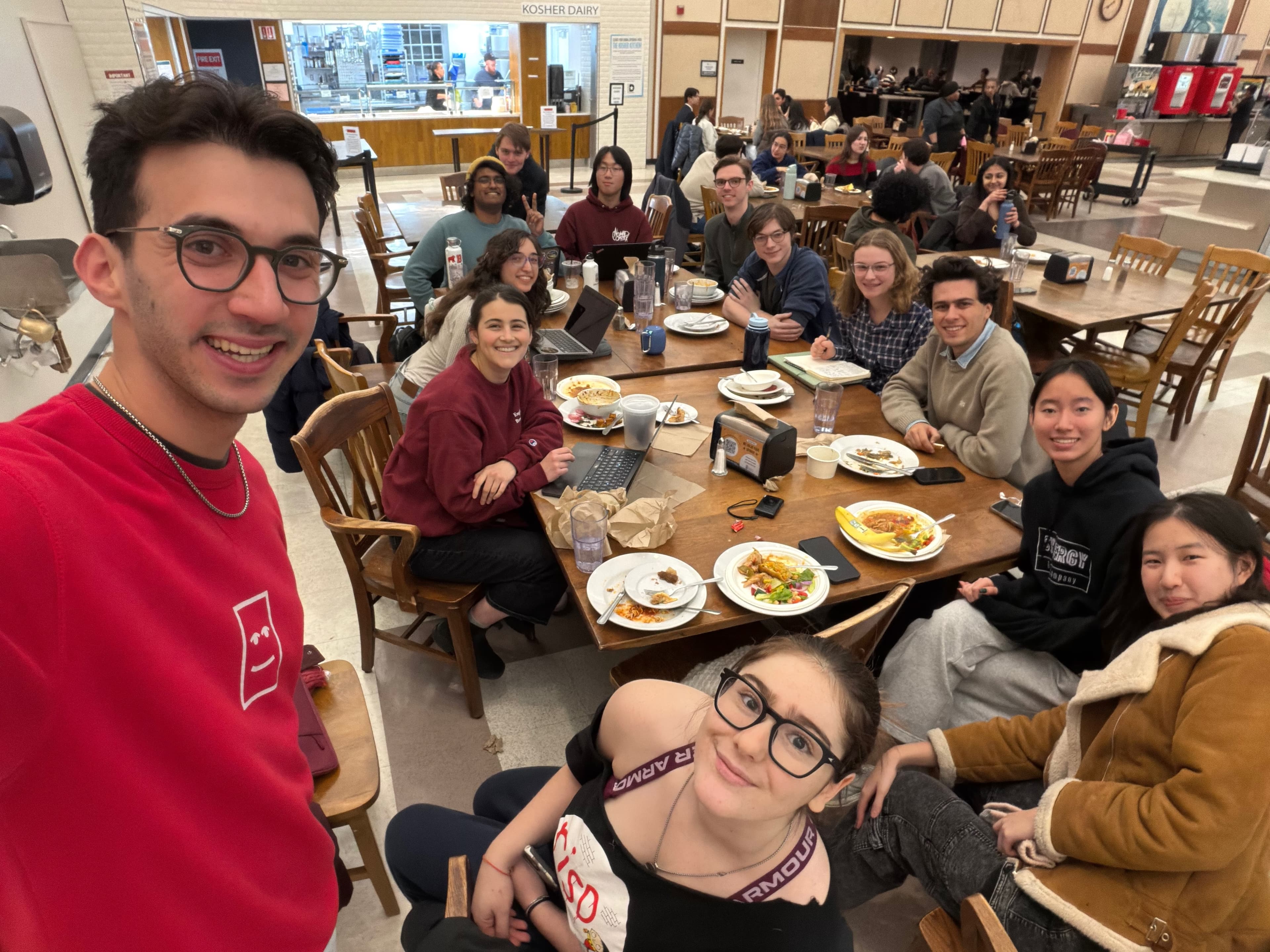 Alex takes a selfie with Talia, Jackie, Chai, Thor (a surprise guest!), Yi, Luke, Aaron, Ella, Siddharta, Irene, Sulan, and Dena gathered around two tables pushed together.